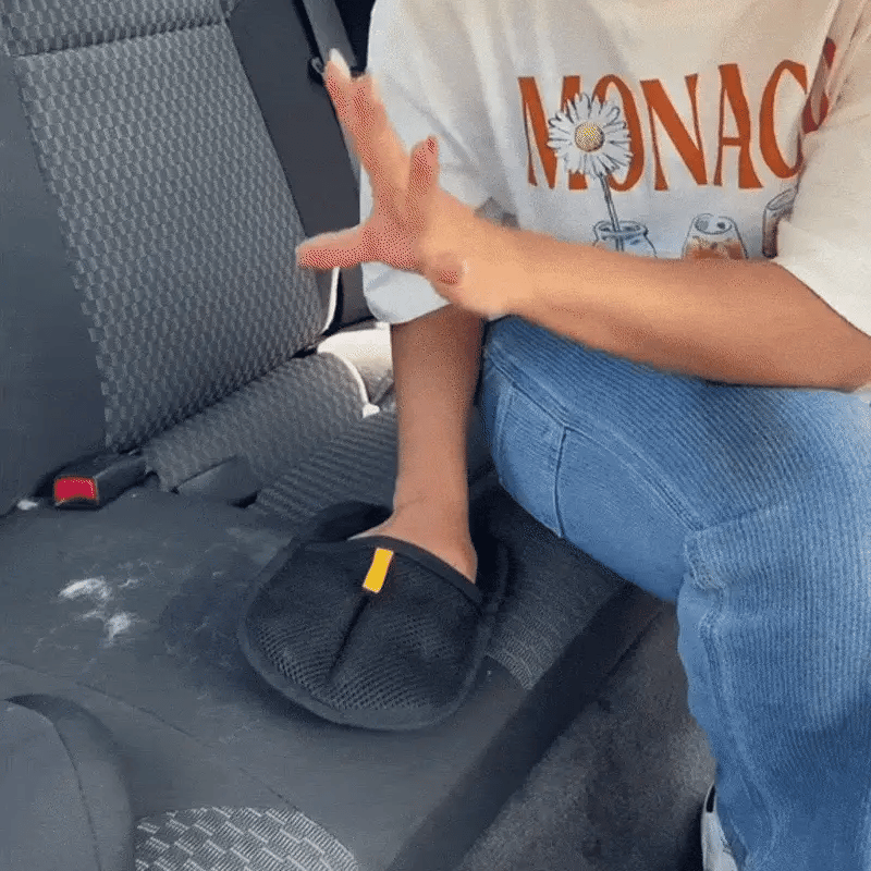 Person using the FurFree glove to lift pet hair off a fabric car seat