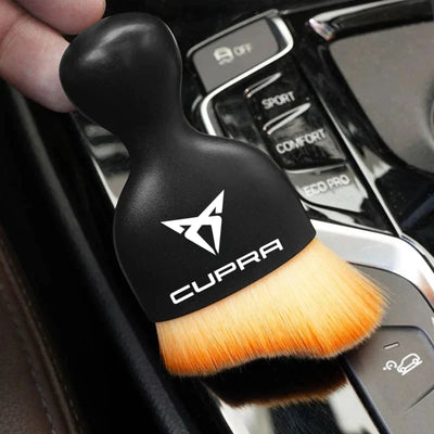 DustMate car detailing brush with the Cupra logo engraved on the handle, held over a car centre console