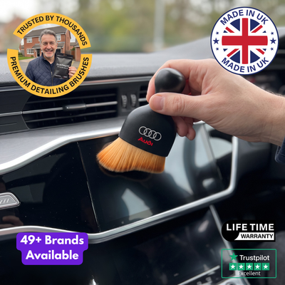 DustMate car detailing brush with the Audi logo engraved on the handle, dusting the edge of a car touchscreen
