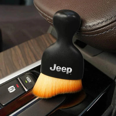 DustMate car detailing brush with the Jeep logo engraved on the handle, next to a car seat