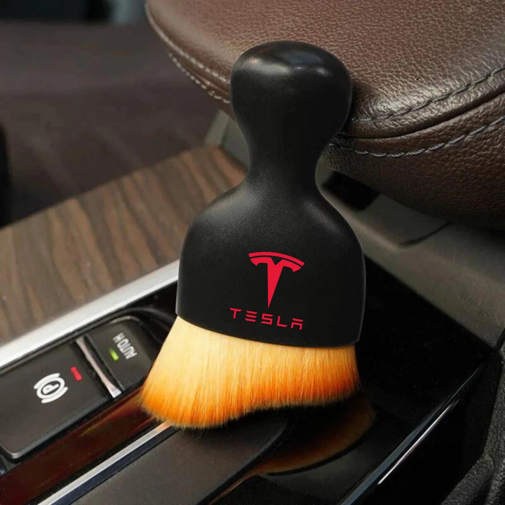 DustMate car detailing brush with the Tesla logo engraved on the handle, next to a car seat