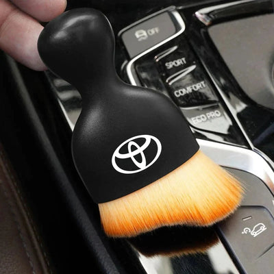 DustMate car detailing brush with the Toyota logo engraved on the handle, held over a car centre console
