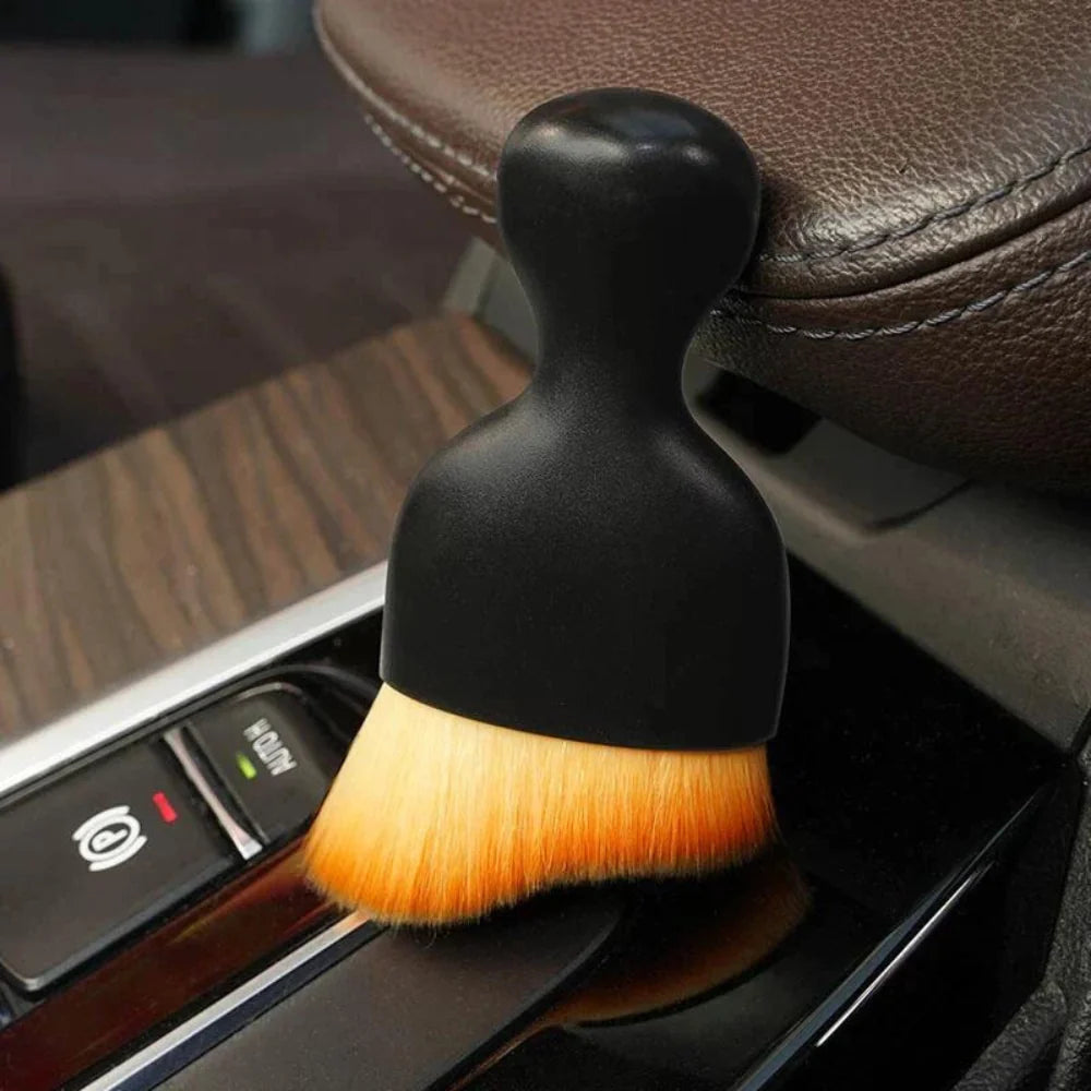 DustMate car detailing brush with a plain black handle and no logo, next to a car seat