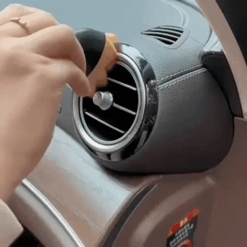 Hand dusting a round car air vent with a DustMate car detailing brush